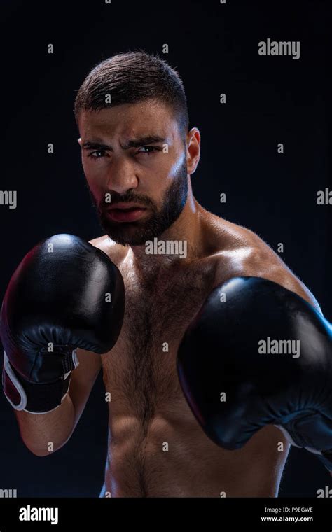 Portrait Of Tough Male Boxer Posing In Boxing Stance Against Black