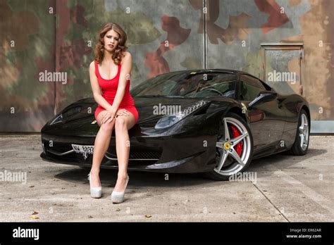 Young Woman Wearing A Red Dress Posing On A Black Ferrari 458 Italia