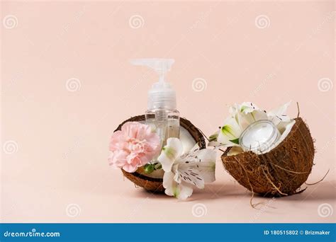 Plastic Bottles With Dispenser Near Flowers Coconut Oil Cream Stock