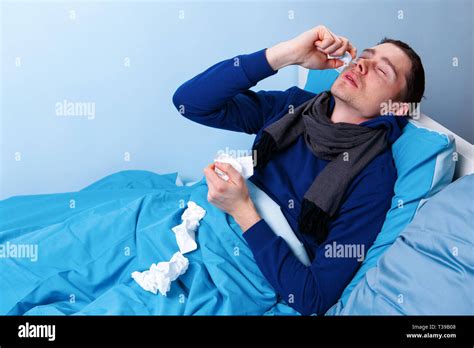 Sick Brunet Male Using Nasal Spray While Lying In Bed Stock Photo Alamy