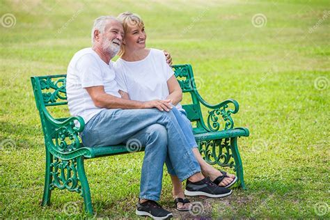 Happy Senior Loving Couple Relaxing At Park Embracing Together In