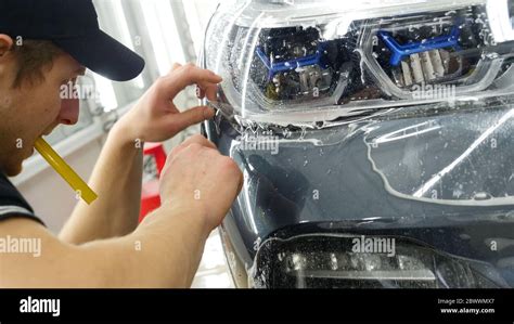 Close up to PPF installation process on a front headlight and hood. PPF ...