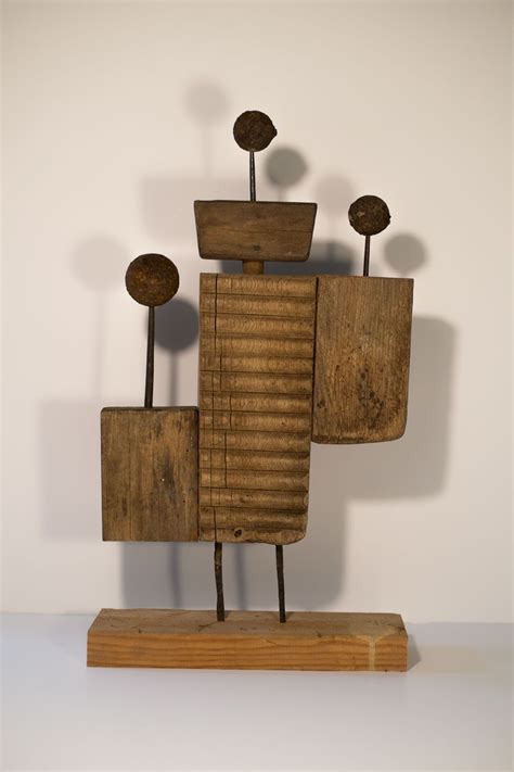 A Wooden Sculpture Sitting On Top Of A White Table Next To Two Metal