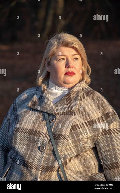 Portrait Of A Plump Middle Aged Woman With Blonde Hair And Bright Painted Lips Illuminated By