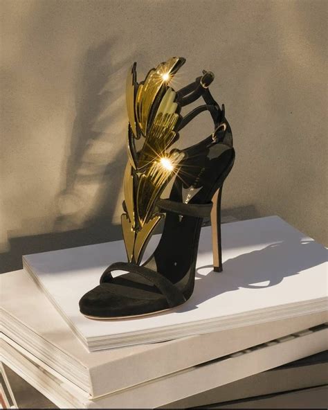 A Pair Of Black And Gold Shoes Sitting On Top Of A Stack Of White Books