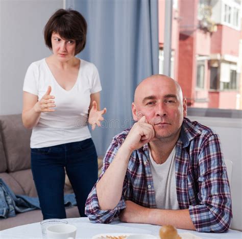 Upset Mature Man Sitting While Quarrel With Wife At Home Interior Stock