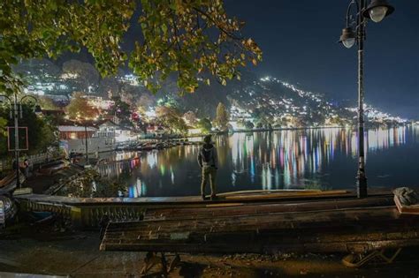 a man standing on top of a boat in the middle of a lake at night