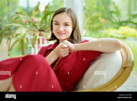 Beautiful Teenage Girl In Red Dress Relaxing On A Terrace At Home