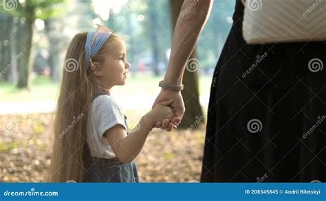 Back View Of Mom And Her Little Daughter Walking Together Holding Hands