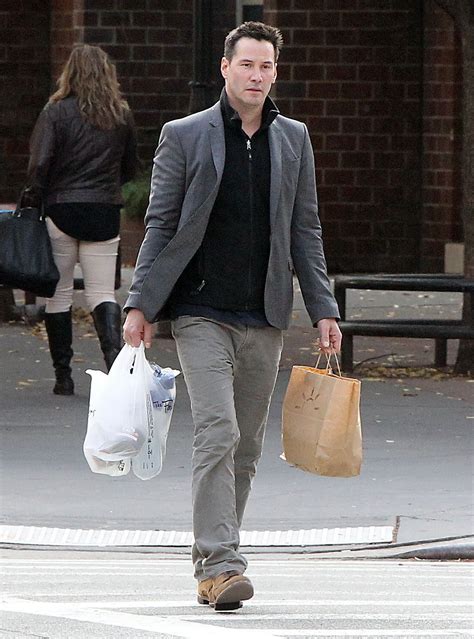 A Man Walking Down The Street Carrying Two Bags And A Shopping Bag In