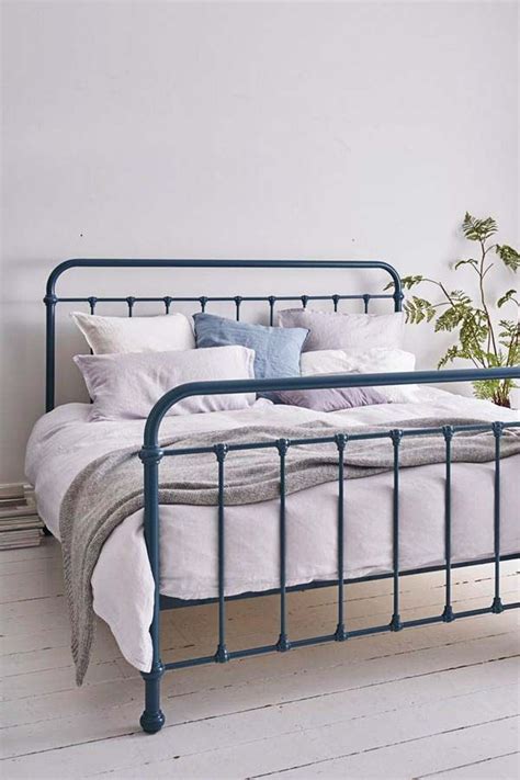 A Bed With White Linens And Blue Metal Frame