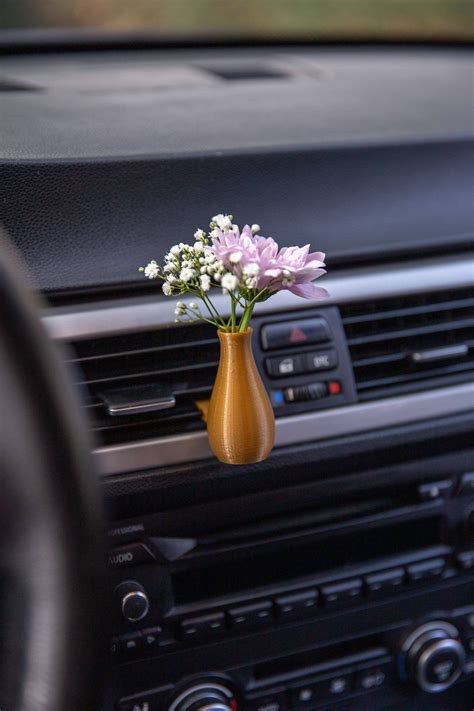 A Small Vase With Flowers In It Sitting On The Dash Board Of A Car S