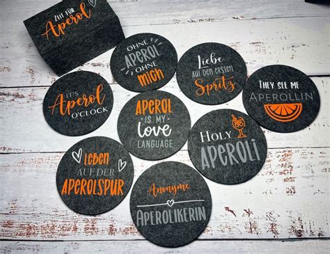 Black And Orange Coasters With Words On Them Sitting On A White Wooden