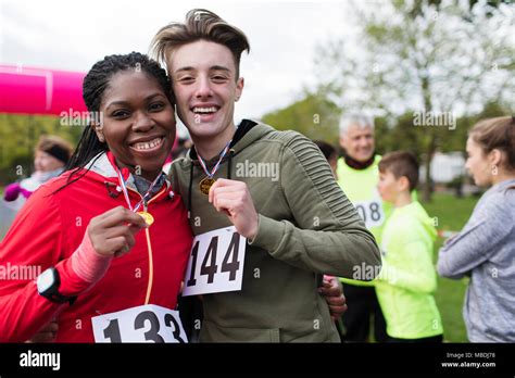 Portrait Smiling Confident Couple Runners Showing Medals At Charity