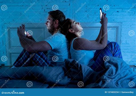 Bored Couple In Bed Addicted To Their Smart Mobile Phones Ignoring Each