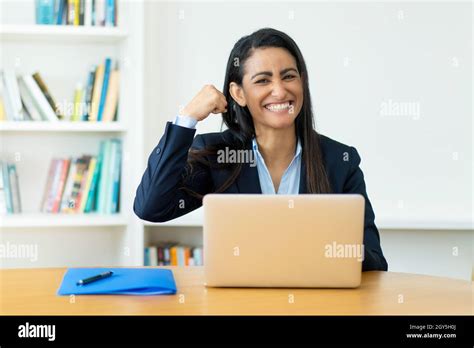 Successful Cheering Hispanic Mature Businesswoman At Computer At Desk