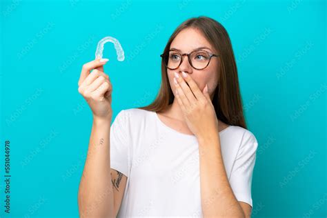 Young Lithuanian woman holding invisible braces isolated on blue ...