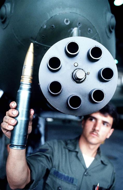 A soldier stands below a GAU-8 Gatling Gun and holds up a 30mm