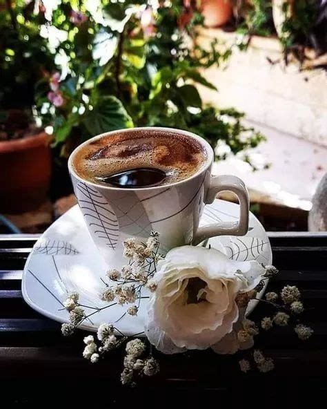 A Cup Of Coffee And Some Flowers On A Table