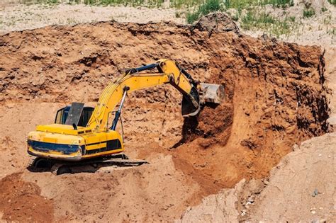 Premium Photo An Excavator In A Sand Pit Loads A Dump Truck With Sand