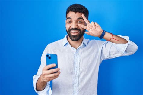 Hispanic Man With Beard Using Smartphone Typing Message Doing Peace