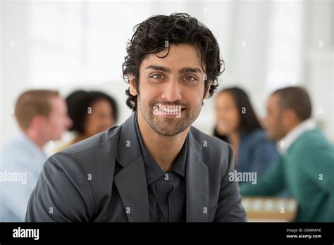 Business Meeting A Group Sitting Down Around A Table A Man Smiling