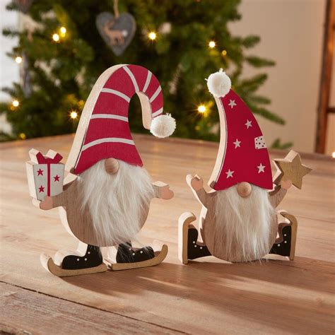 Two Wooden Gnomes With Christmas Decorations On A Table