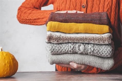 Premium Photo A Woman Holding A Stack Autumn Warm Knitted Sweaters