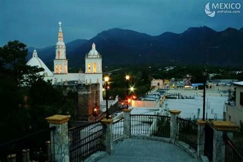 A View Of A City At Night With Mountains In The Background