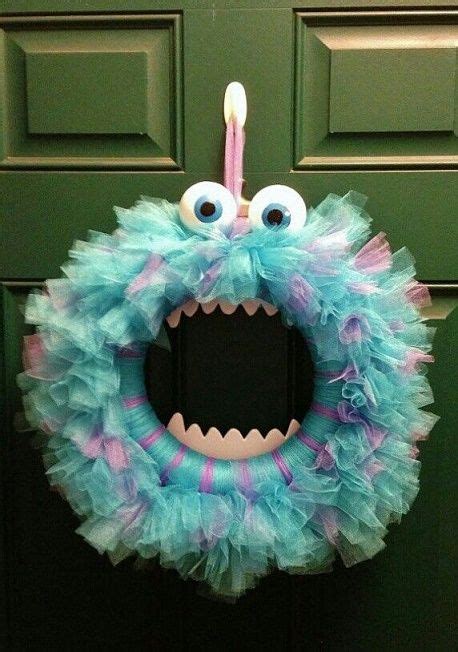 A Blue And Pink Wreath With Googly Eyes Hanging On A Green Door Frame