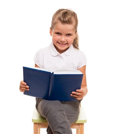 Bambina Che Si Siede Su Una Sedia Con Il Libro Blu E Sorridere Immagine