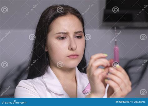 Attractive Brunette Nurse In White And Pink Medical Gown With A Syringe In Gray Room Healthcare