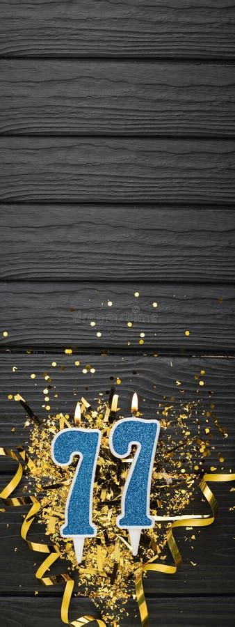 Number 77 Blue Celebration Candle And Gold Confetti On Dark Wooden