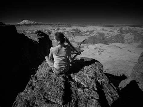 Premium Photo Rear View Of Woman Sitting On Rock Against Sky