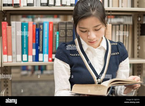 Attractive Young Girl Sitting On The Floor In Front Of A Bookshelf