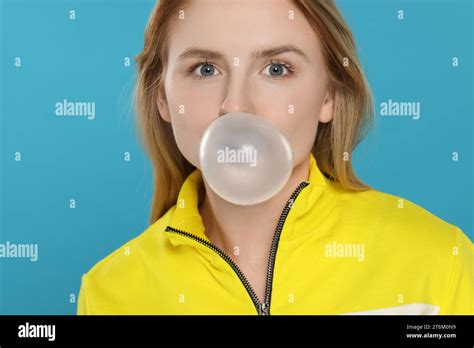 Beautiful Young Woman Blowing Bubble Gum On Light Blue Background Stock