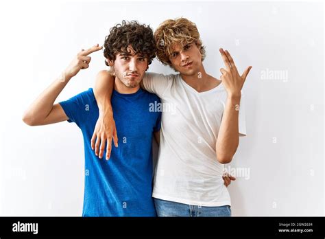 Un jeune couple gay debout ensemble sur un arrière plan isolé de tir et de se tuer pointant de