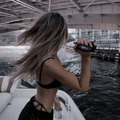 A Woman On A Boat With Her Hair Blowing In The Wind And Holding A Water