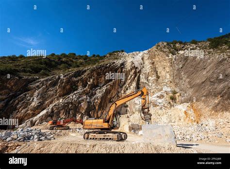 Orange Tracked Excavators With Jackhammer In A White Marble Quarry