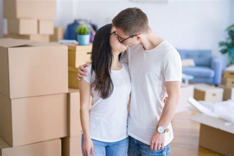 Young Beautiful Couple Kissing Wearing Glasses Standing At New Home