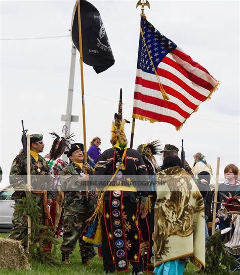 Several People Dressed In Native American Clothing And Holding Flags