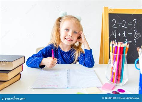 Happy Cute Industrious Child Is Sitting At A Desk Indoors Stock Image