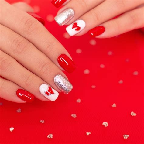 Hermosas manos femeninas con uñas de manicura rojas corazones y diseño