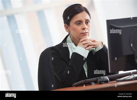 Mature Businesswoman Looking At Computer With Concentration Stock Photo