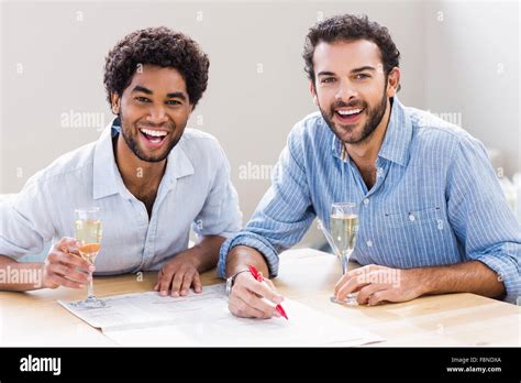 Happy Gay Couple Drinking Champagne And Writing On Newspaper Stock