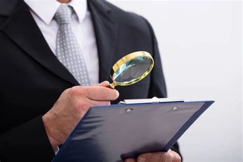 Businessman Examining Documents With Magnifying Glass Stock Photo