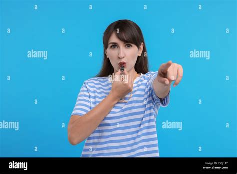 Woman Blowing Whistle On Light Blue Background Stock Photo Alamy