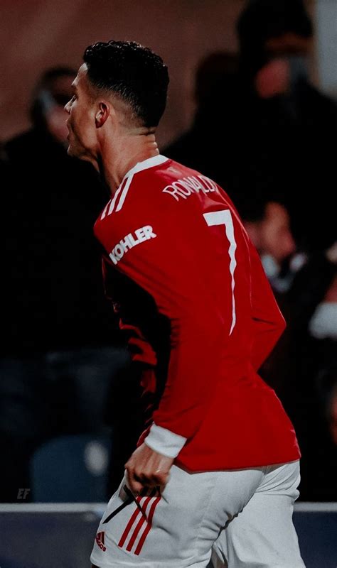 A Man In Red And White Soccer Uniform Running With His Foot On The