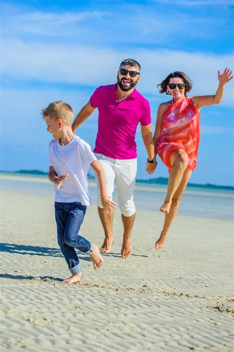 Famille De Trois Fonctionnant Le Long Du Temps De Plage De Rire Et