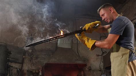 A Blacksmith Forged A Sword In A Forge He Holds A Red Hot Sword With